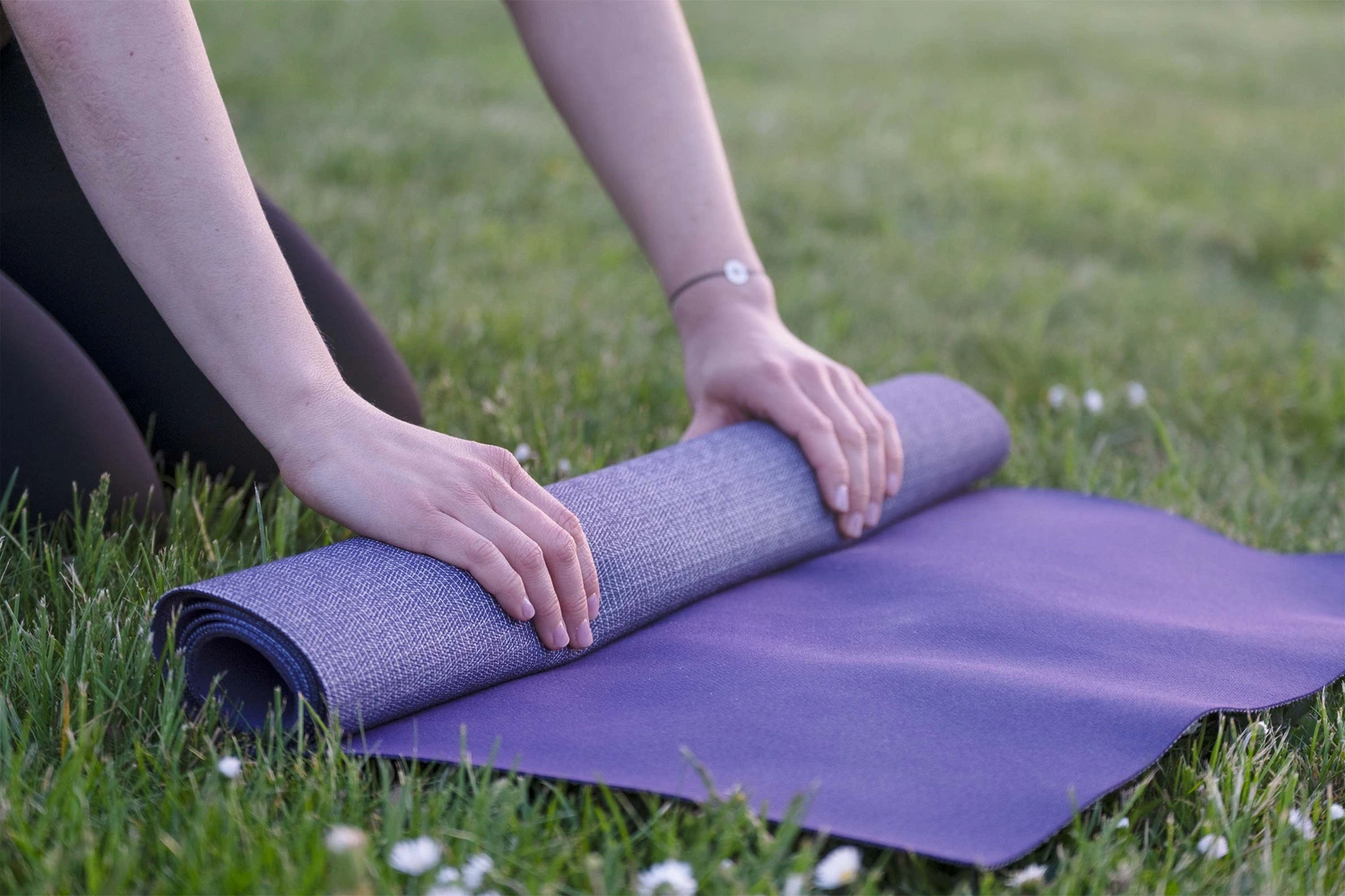 Eine Yogamatte wird auf der Wiese eingerollt